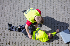 man laying on ground being comforted by another man